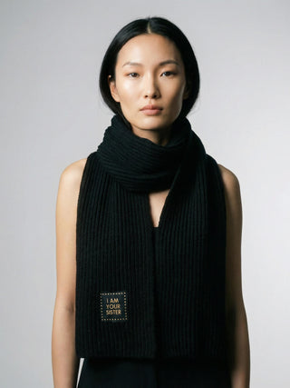 Woman wearing a black scarf with a visible brand logo on a gray background