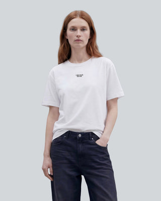 Woman wearing a white I am your sister t-shirt on a plain background